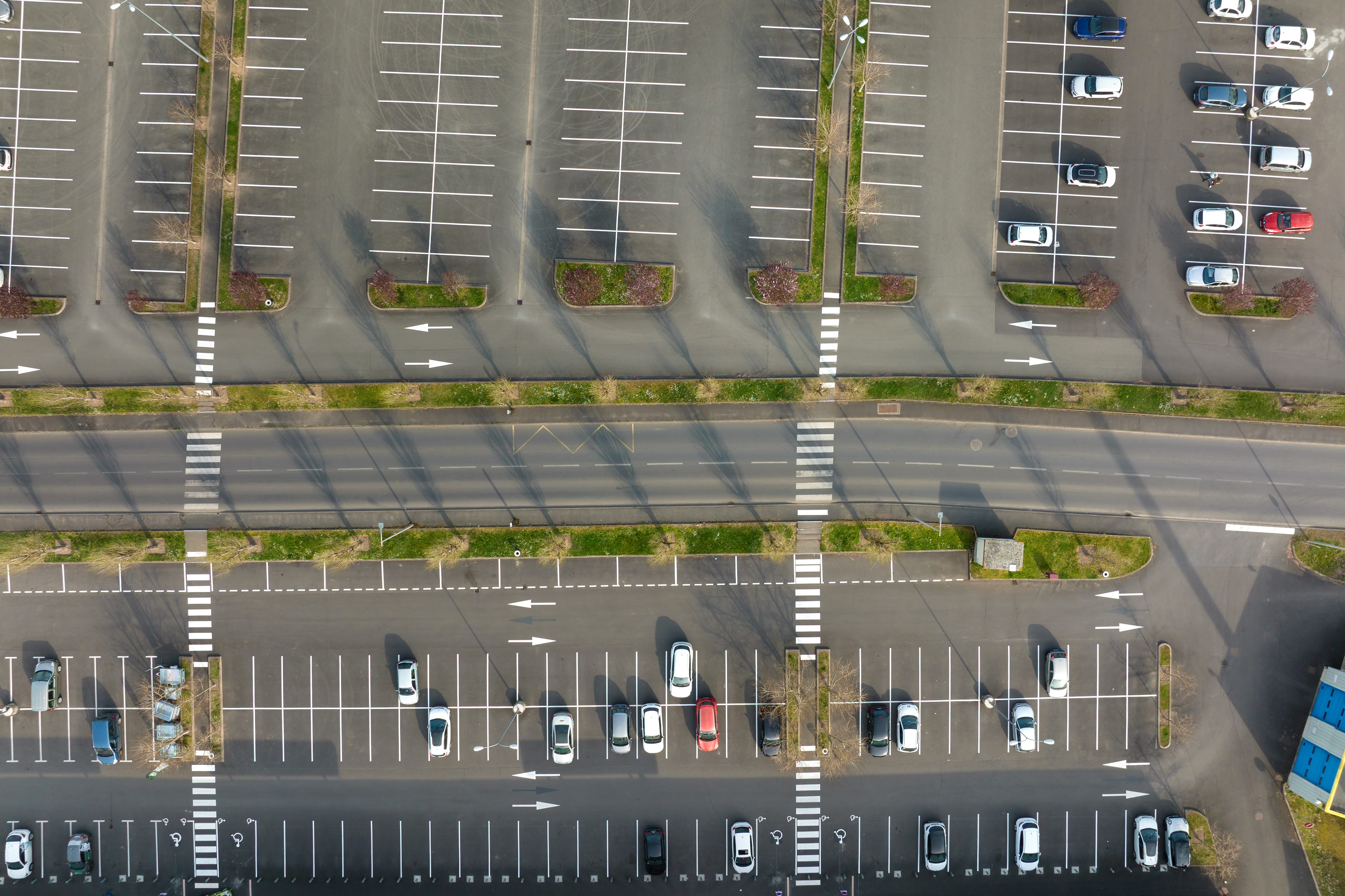 Aerial view of many colorful cars parked on parking lot with lines and markings for parking places